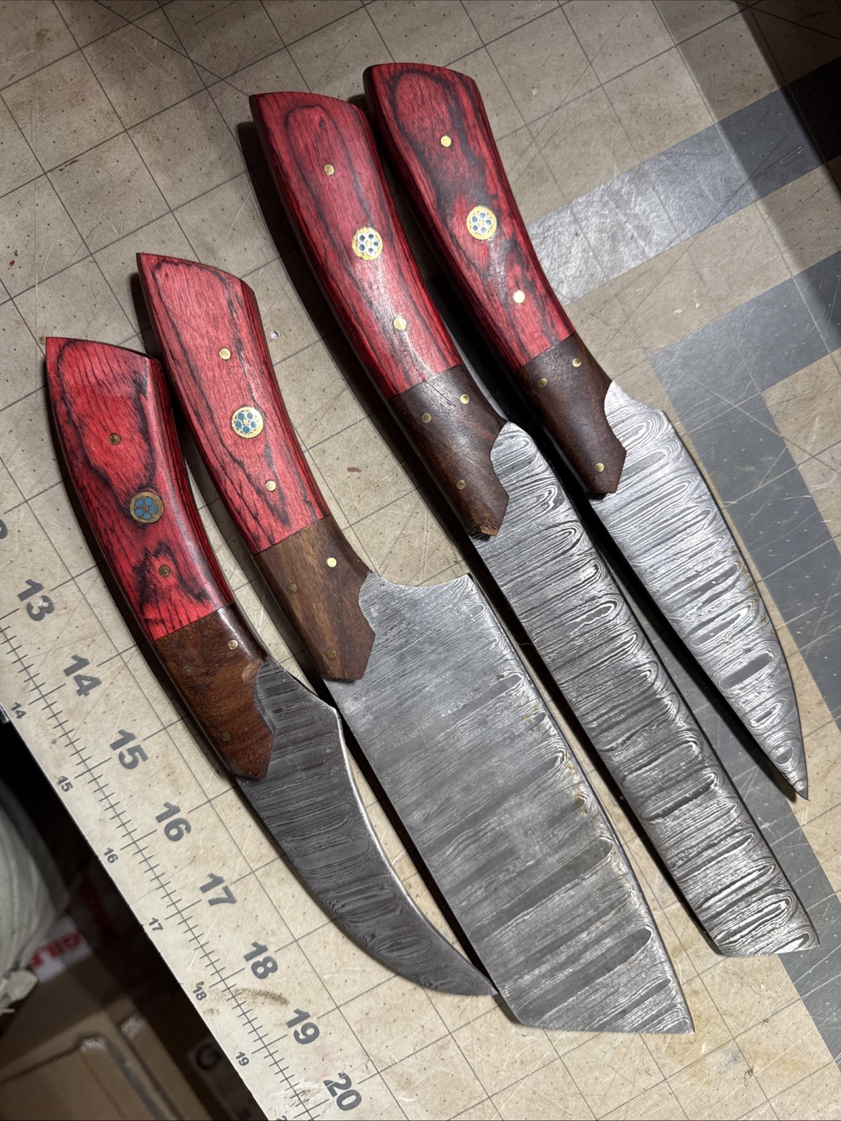 A set of 4 handmade Damascus? steel kitchen knives with Red Wood Handles Used